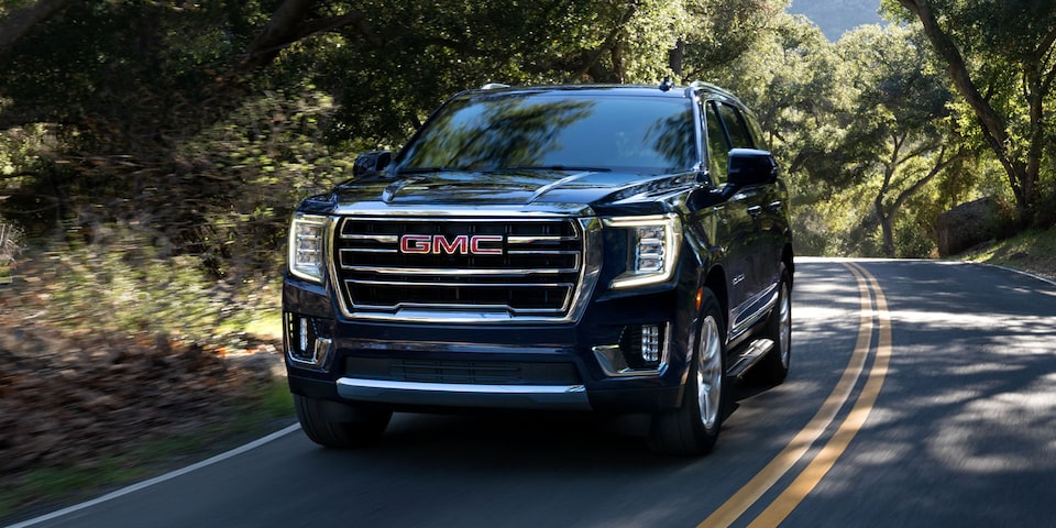 Front side profile of the 2024 GMC Yukon driving on the road.