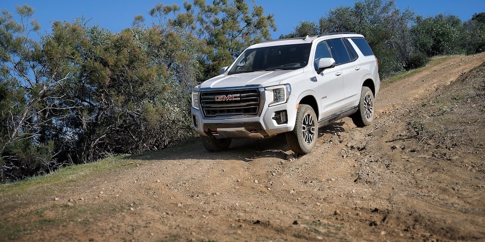 Front side profile of the 2024 GMC Yukon AT4 driving outdoors.