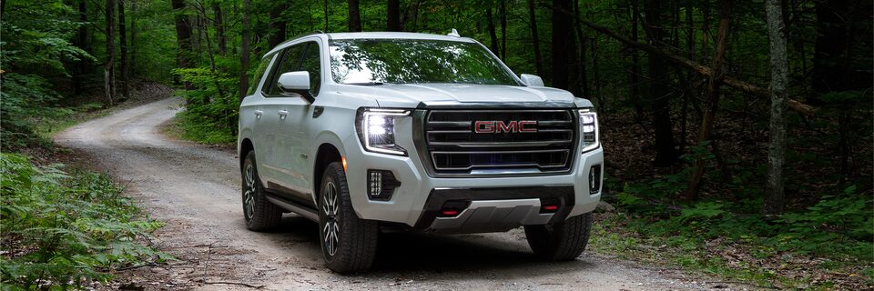 GMC Yukon AT4 2024 en mouvement sur une route forestière.