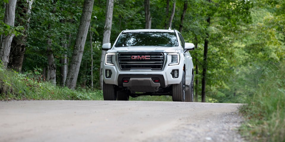 GMC Yukon AT4 2024 en mouvement sur une route forestière.
