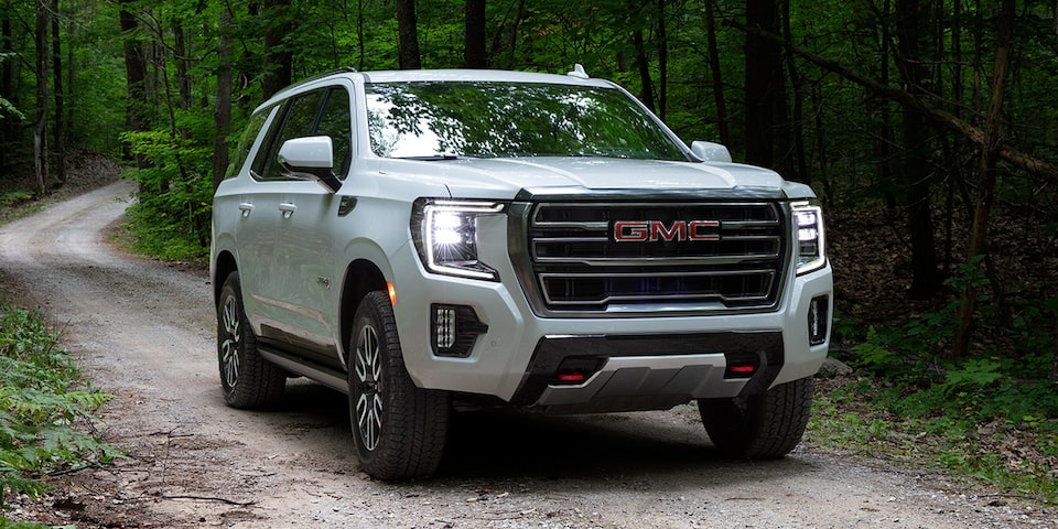 2024 GMC Yukon AT4 driving alone on a forest road.