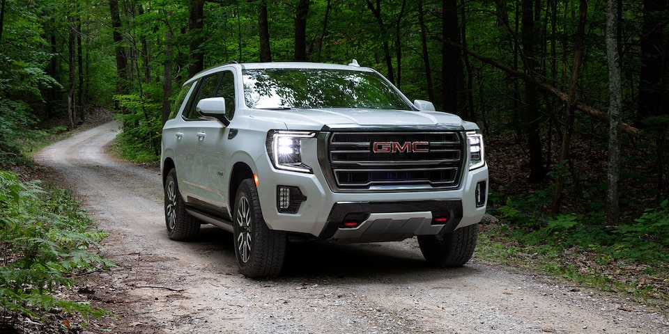 2024 GMC Yukon AT4 driving alone on a forest road.