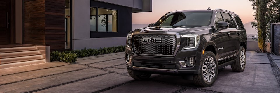 Front-side view of the 2024 GMC Yukon Denali Ultimate exiting a modern home.