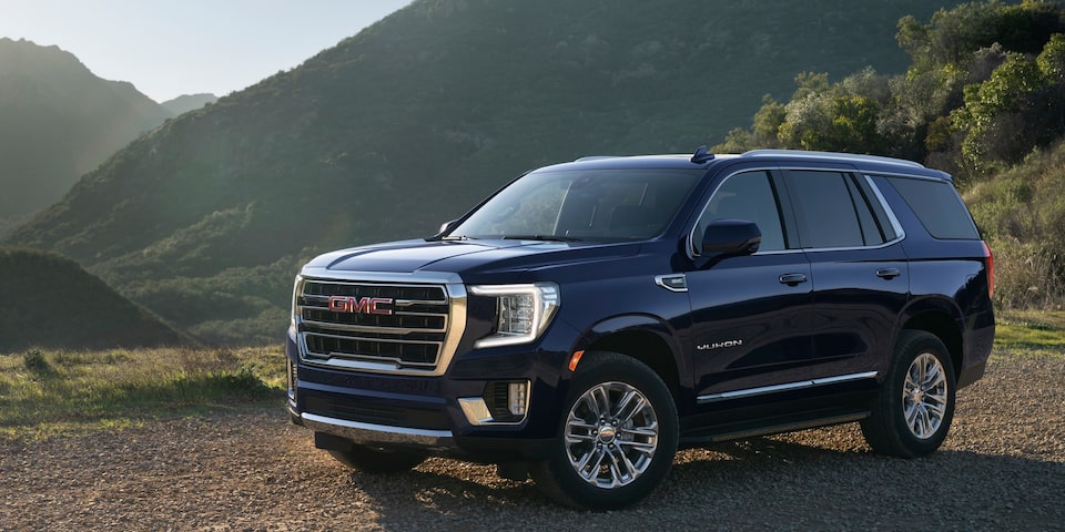 2024 GMC Yukon SLT driving on a hillside terrain.