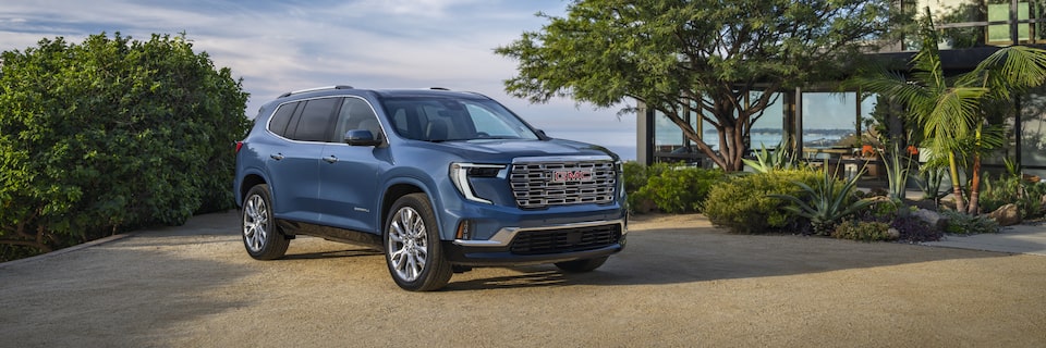 Side view of a 2025 GMC Acadia Denali parked outside a resort.