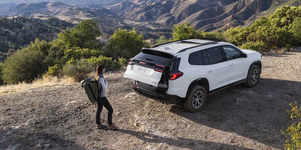 Une personne ouvrant le coffre arrière du GMC Acadia Élévation 2025.