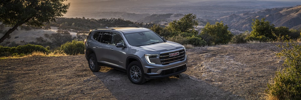Vue latérale avant du GMC Acadia Élévation 2025 stationné seul près des arbres.