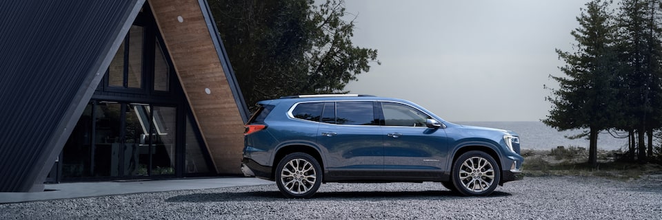 Vue latérale du GMC Acadia 2025 stationné devant une maison.