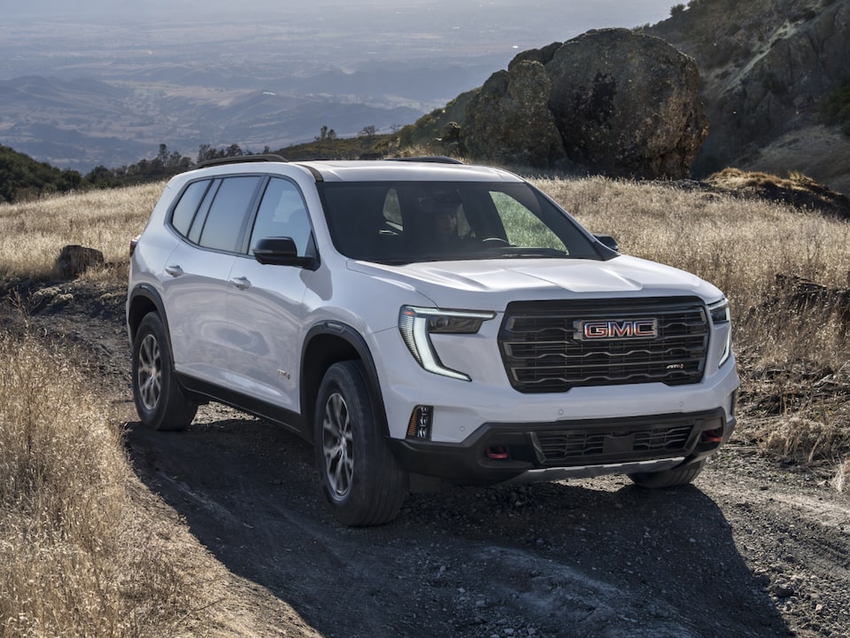 Vue latérale avant du GMC Acadia 2025 en mouvement seul sur une colline.