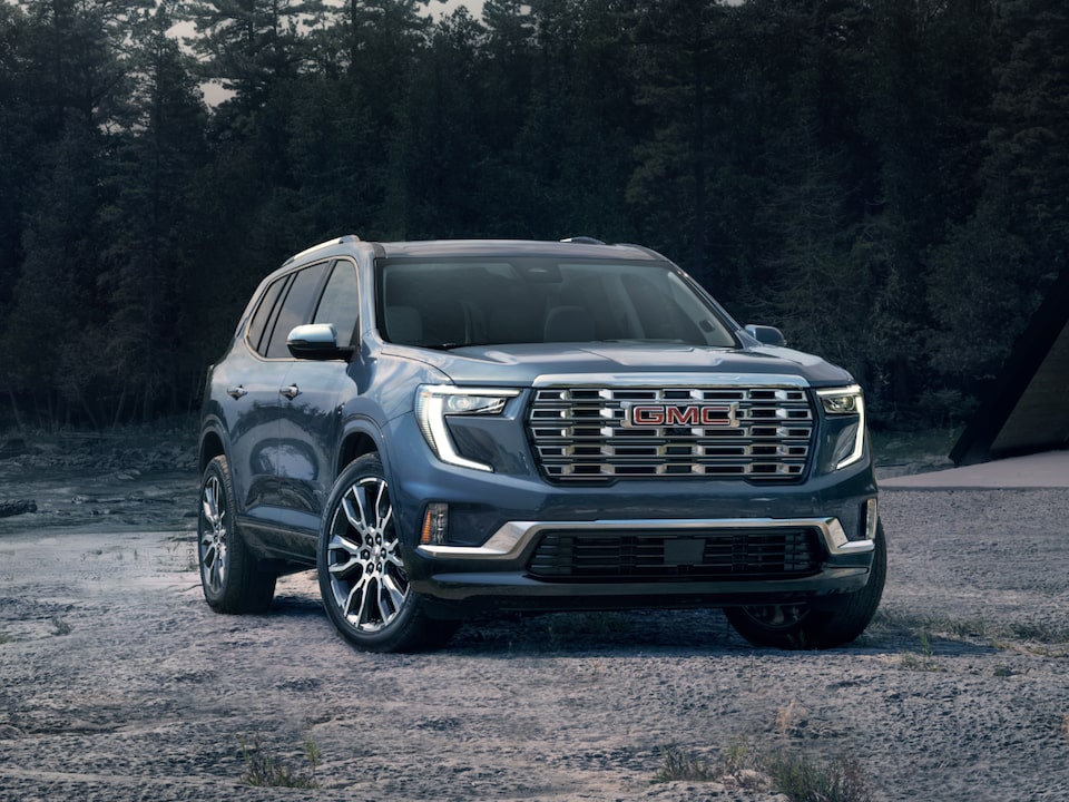 Vue latérale avant du GMC Acadia 2025 stationné devant une maison durant la nuit.