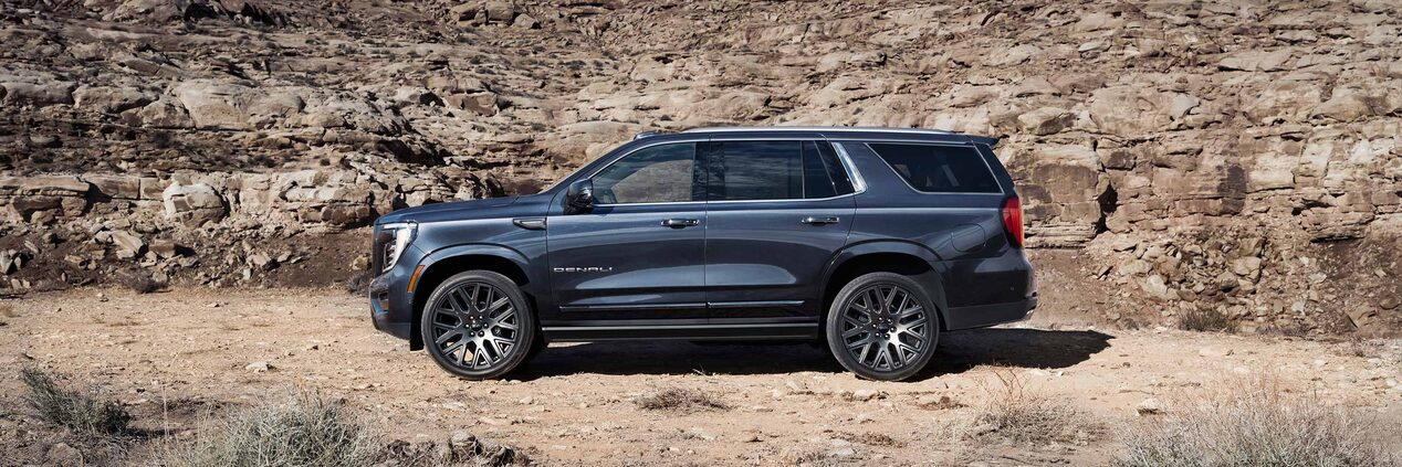 Side view of the 2025 GMC Yukon SUV parked in a rocky terrain.