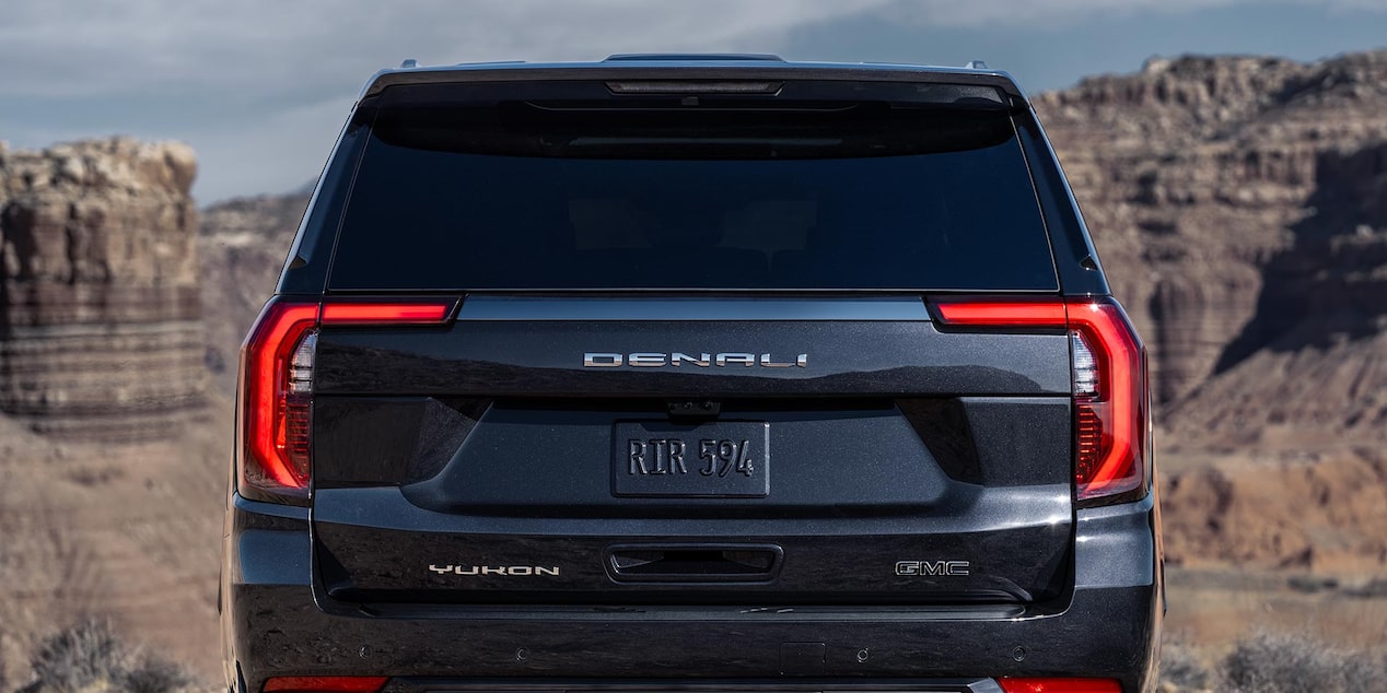Back view of the 2025 GMC Yukon SUV with canyon rocks in the distance.
