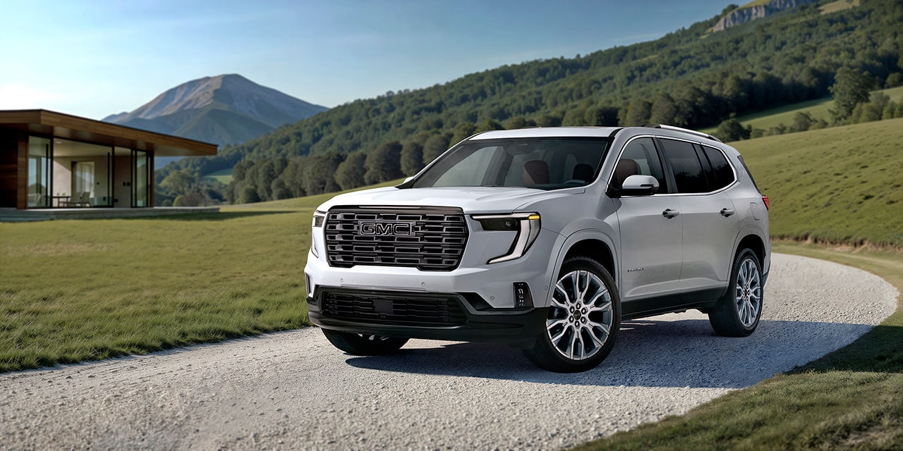 Front Three-Quarters View of a 2026 GMC Acadia Denali Luxury Driving on the Road.