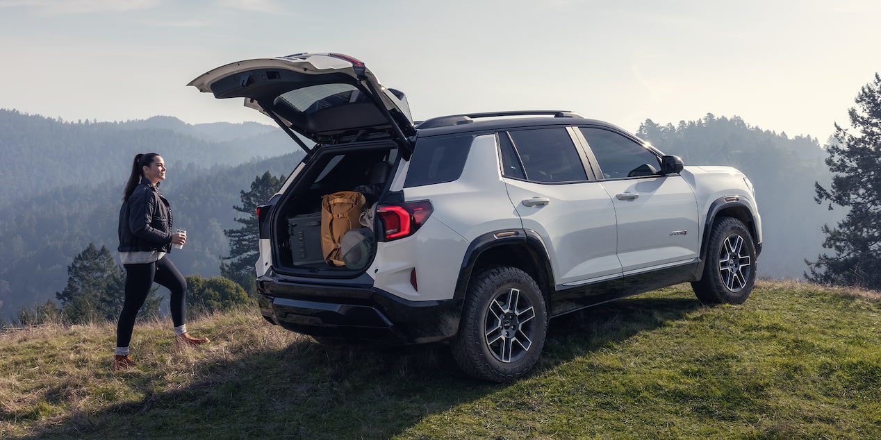 Rear View of the Open Tailgate on the 2026 GMC Terrain AT4 Small Off-Road SUV While A Person Unloads the Cargo.