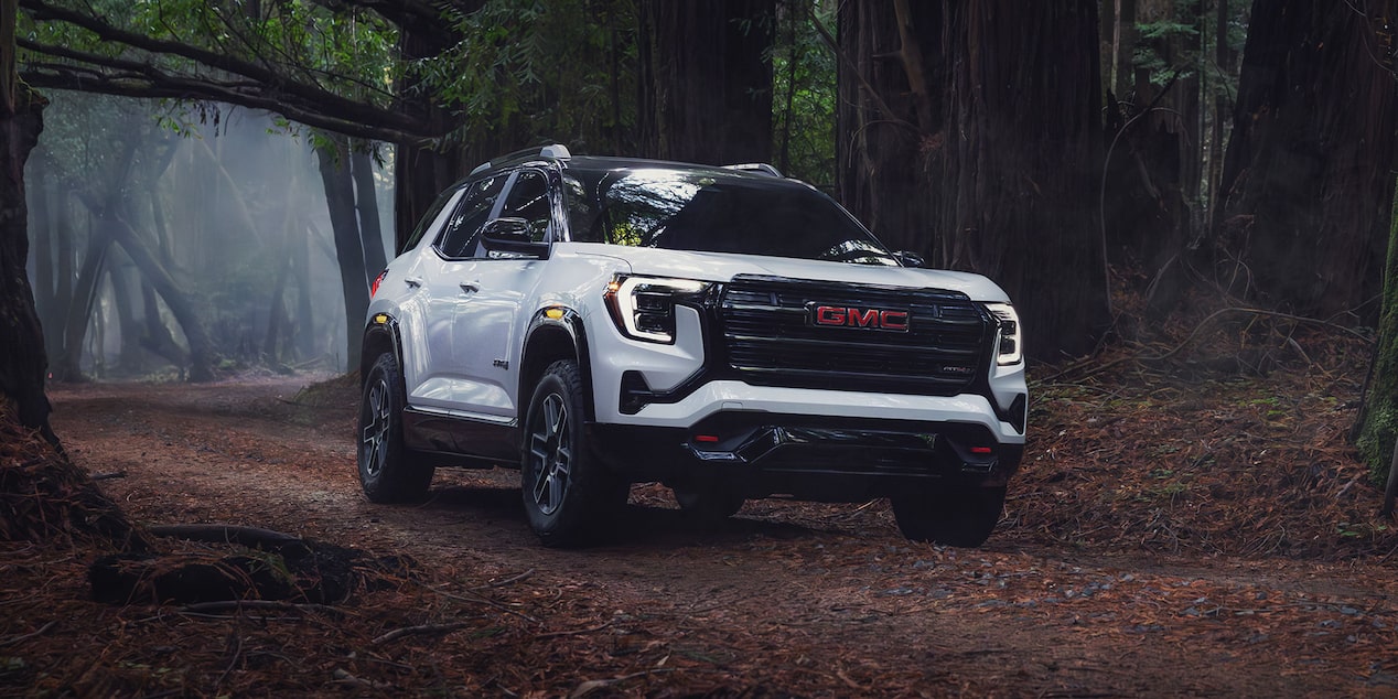 Front-side view of the 2026 GMC Terrain AT4 driving alone in an eerie forest.