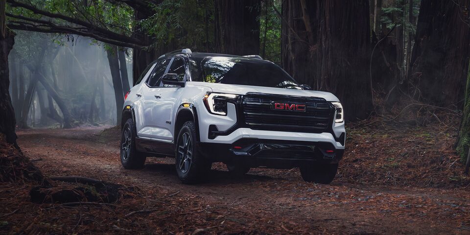 Front-side view of the 2026 GMC Terrain AT4 driving alone in an eerie forest.