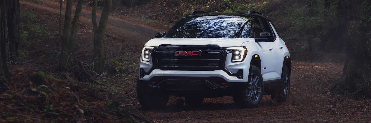 Front view of the 2026 GMC Terrain AT4 driving alone in the woods.