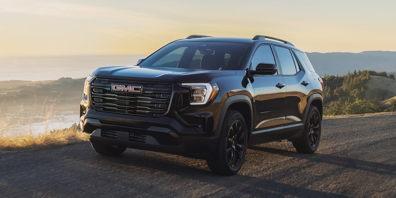 Front-side view of the 2026 GMC Terrain Denali driving alone in a forest road.