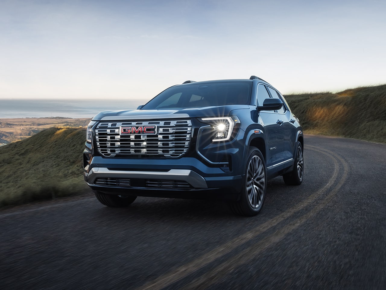 Front Three-Quarters View of a 2026 GMC Terrain Denali Luxury SUV Driving Down the Coast.