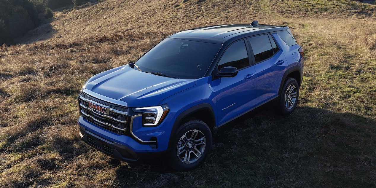 Vue aérienne d’un VUS compact GMC Terrain Élévation 2026 bleu stationné dans un pré.