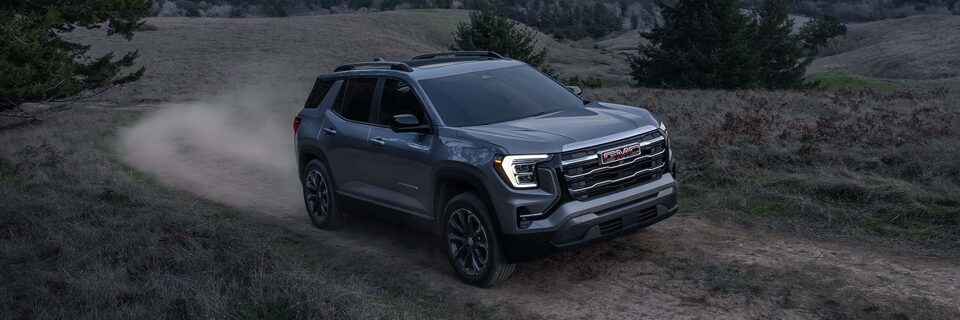 Le VUS compact GMC Terrain Élévation 2026 en mouvement sur une route de terre au coucher du soleil.