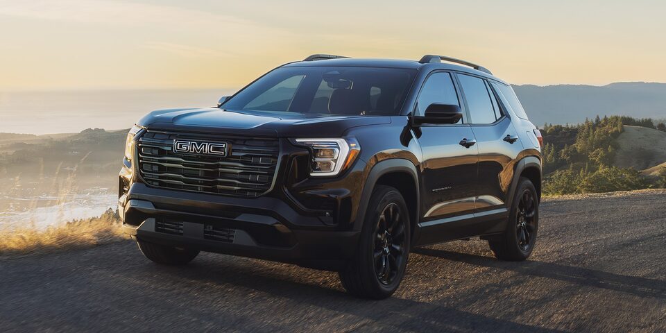 Vue latérale avant du VUS compact GMC Terrain Élévation 2026 en mouvement sur une route côtière.