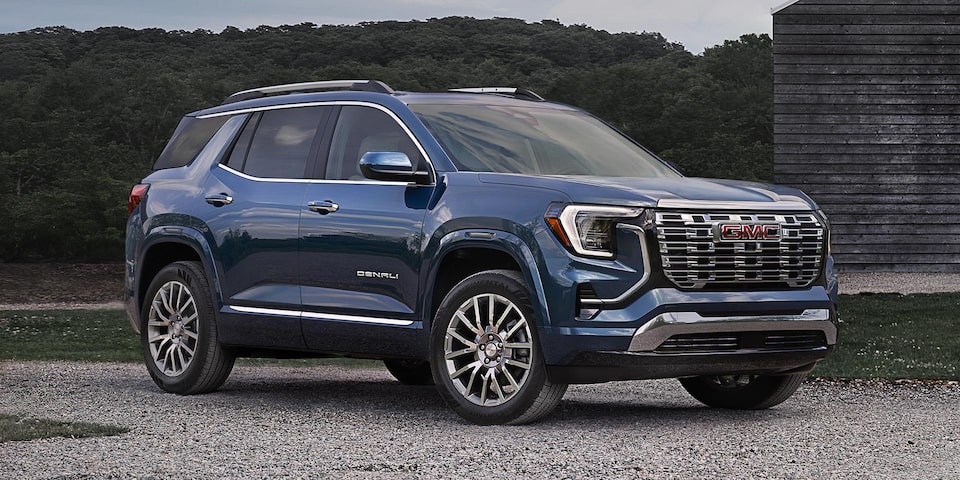 Front-side view of the 2026 GMC Terrain Denali parked near a wooden structure.
