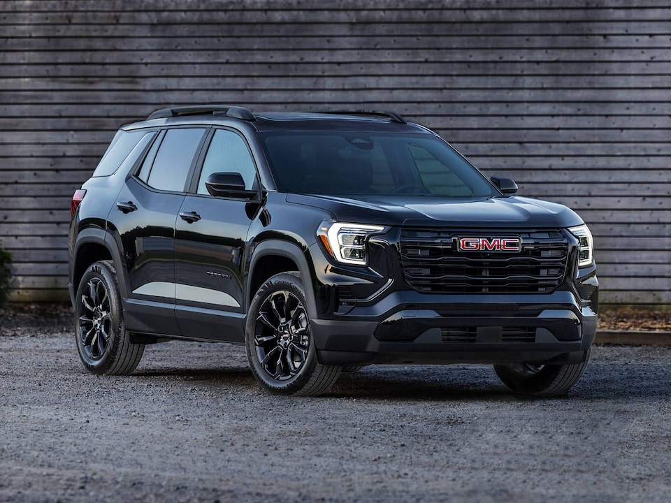 Front-side view of the 2026 GMC Terrain Black Edition parked near a wooden house.