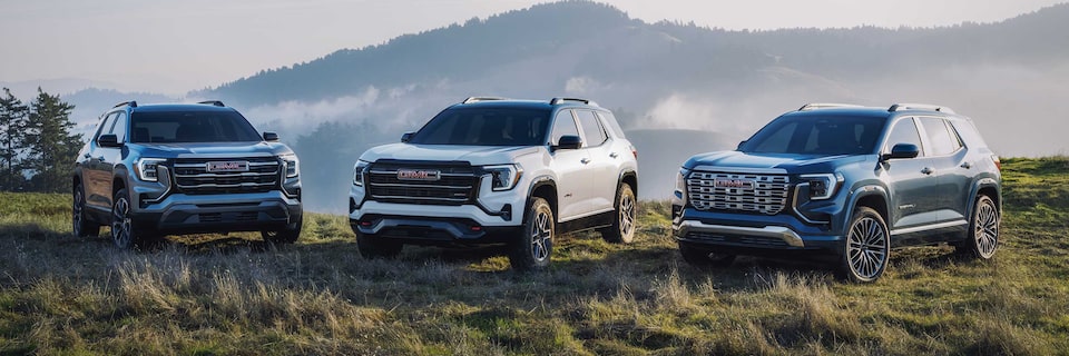 Three 2026 GMC Terrain vehicles parked beside each other by the mountainside.