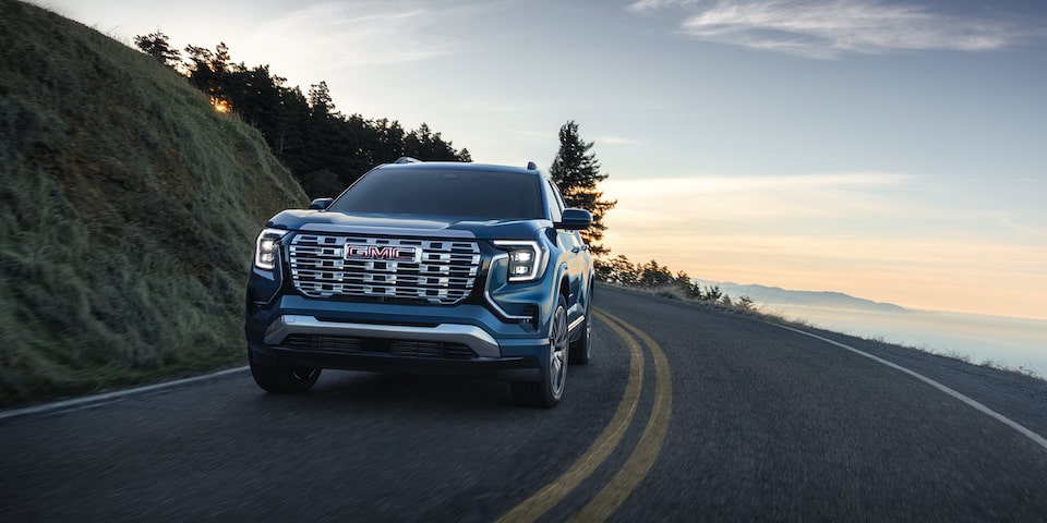 Front view of the 2026 GMC Terrain Denali driving alone on a seaside road.
