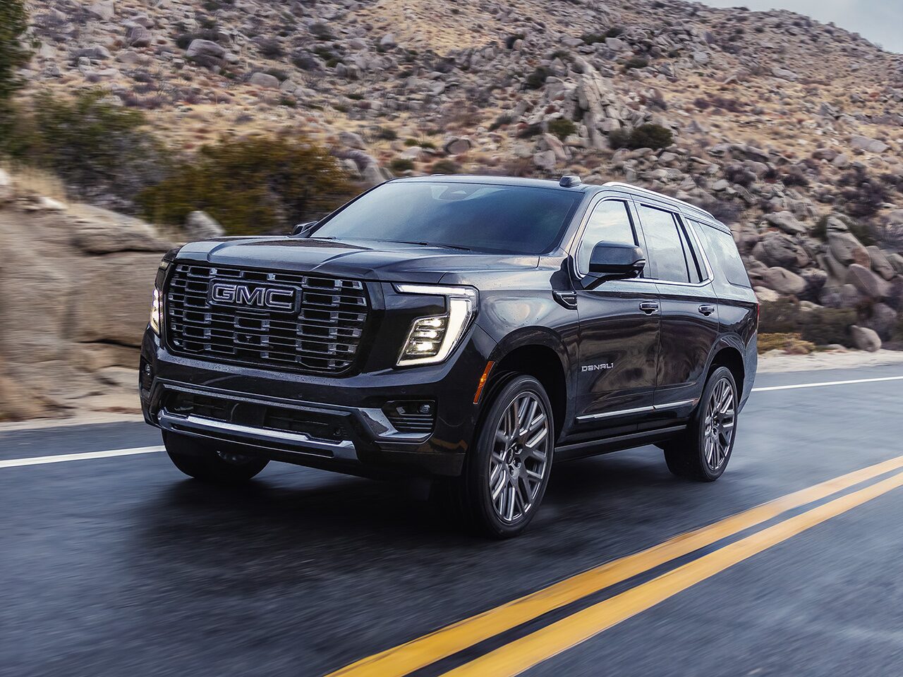 Le VUS de luxe à trois rangées GMC Yukon Denali 2026 en mouvement seul sur la route.