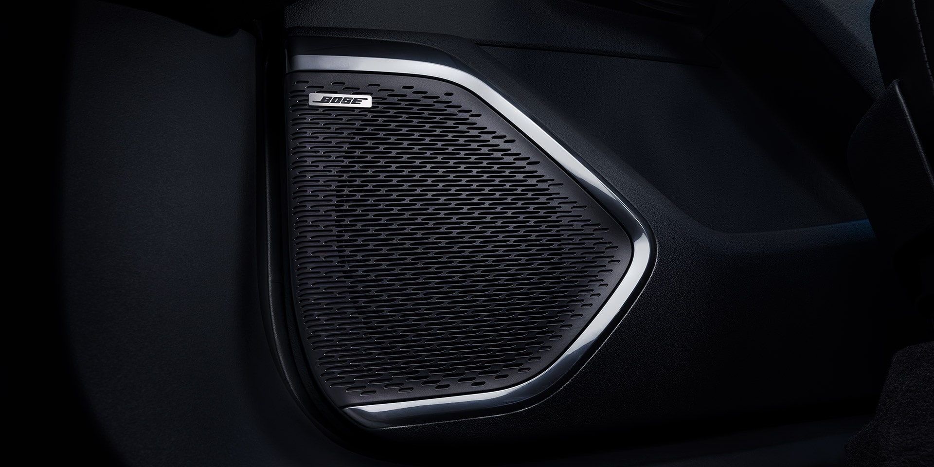 Un gros plan sur la calandre d’un haut-parleur Bose avec une garniture argentée à l’intérieur d’un VUS GMC Acadia 2027.