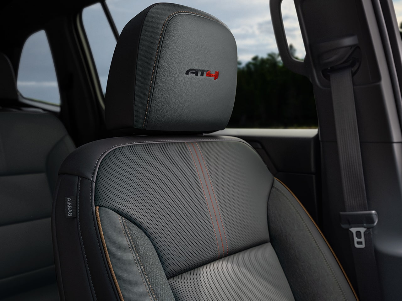 Une photo intérieure du siège en cuir gris perforé d’un VUS GMC Acadia AT4 2027 avec des coutures orange et un logo AT4.