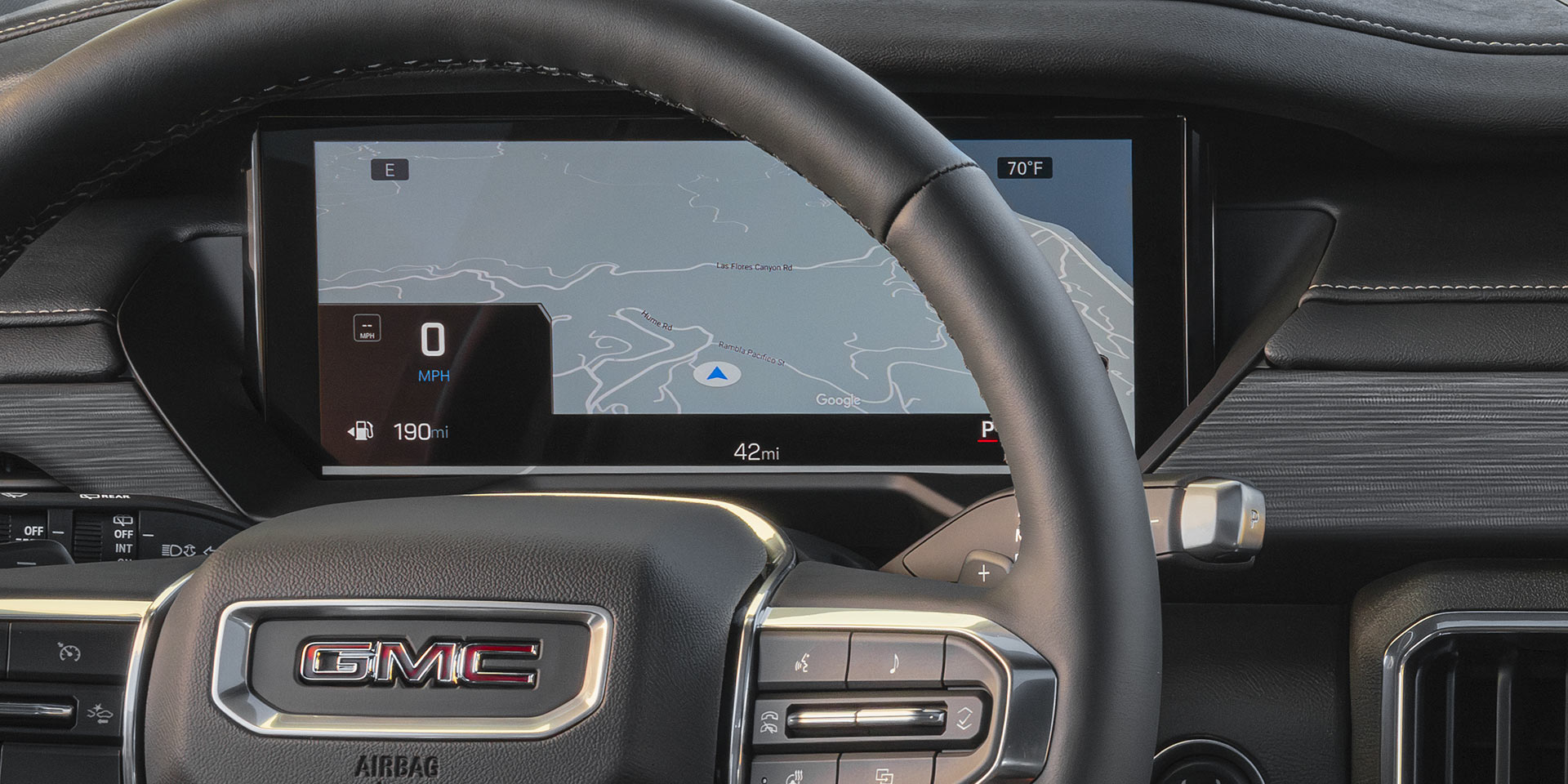 Un gros plan du volant de la GMC Acadia 2027 et un affichage numérique affichant une carte.