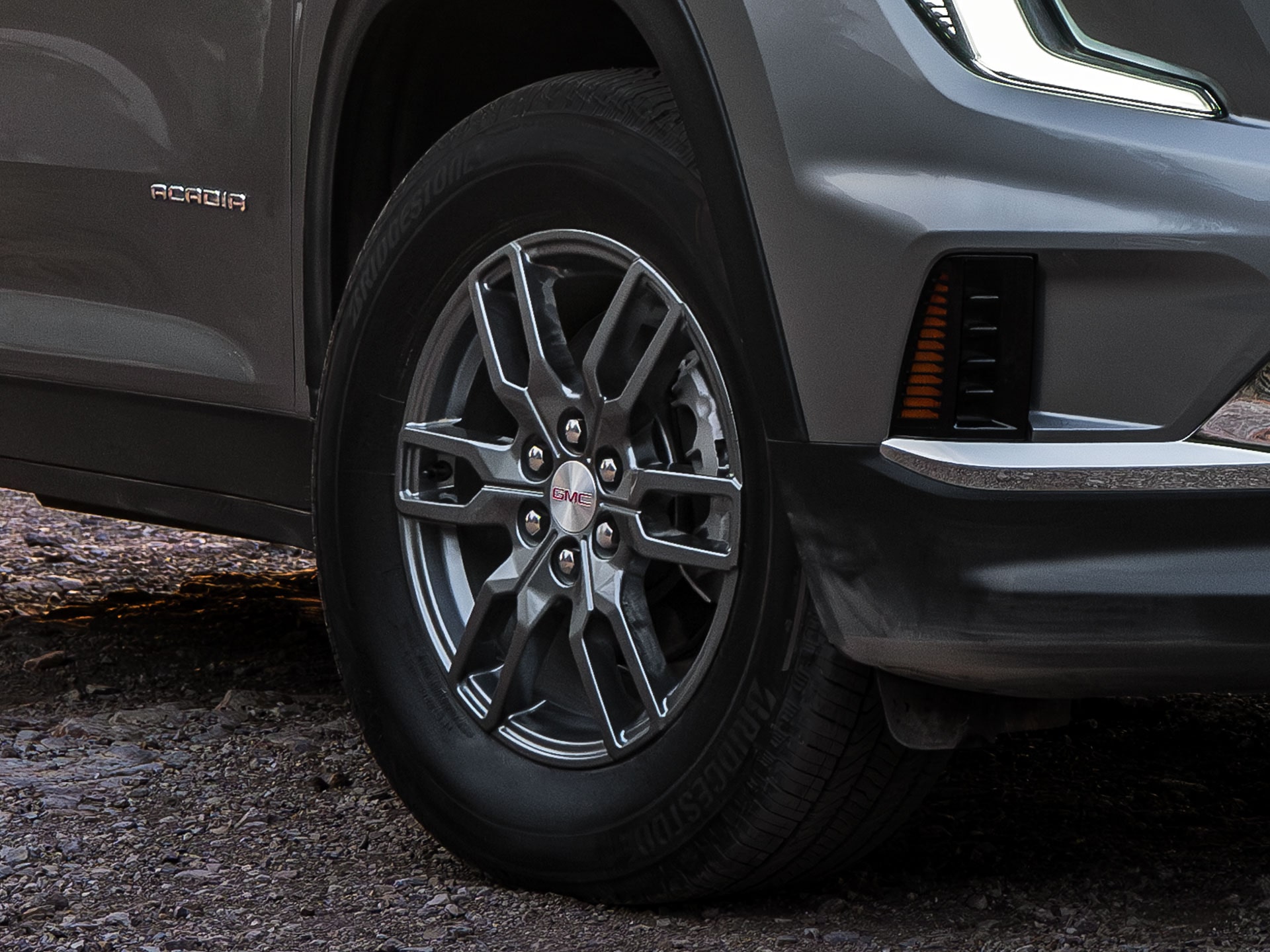 Gros plan de la section inférieure avant et d’une roue grise à rayons multiples d’un VUS GMC Acadia gris 2027.