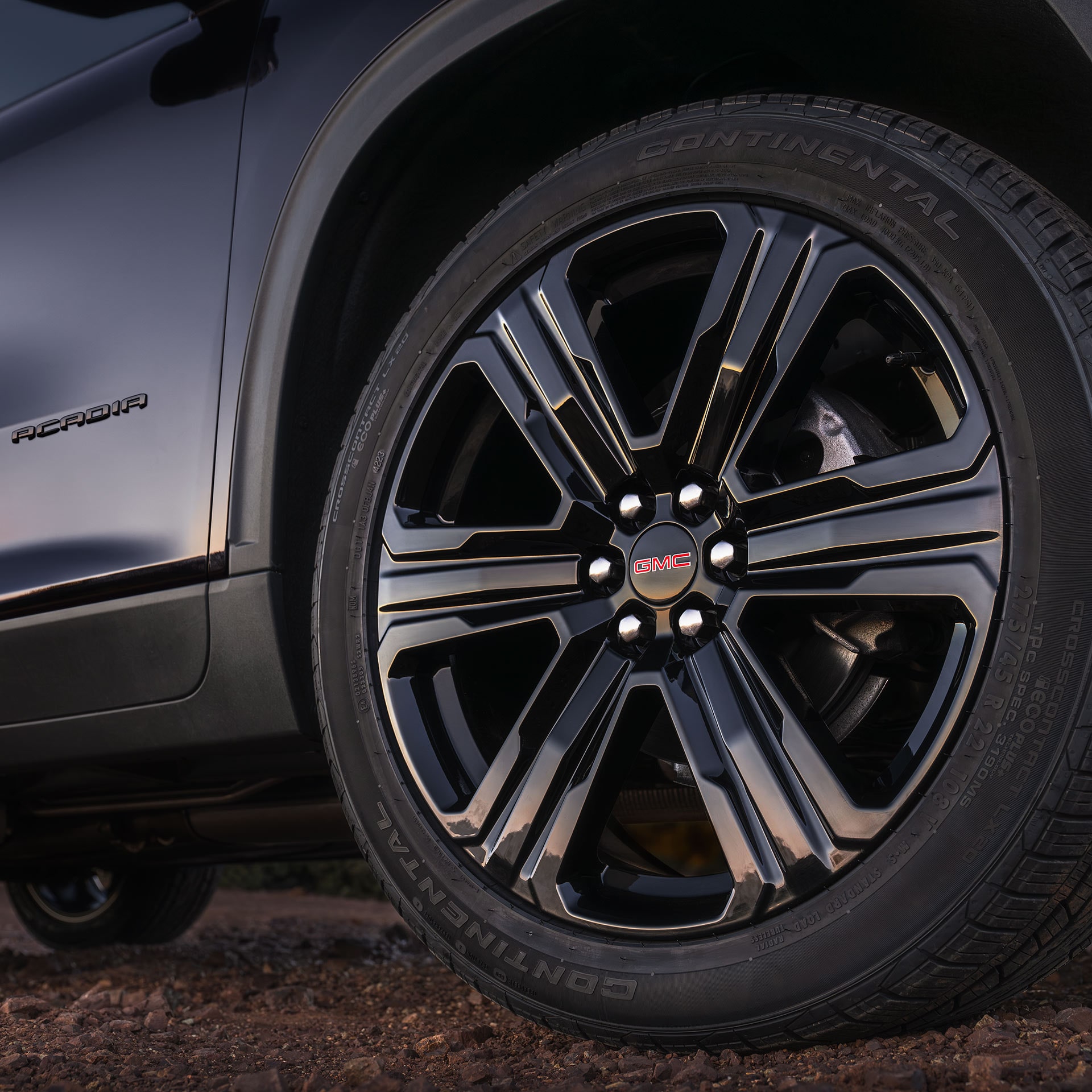 Un gros plan de la roue noire de la GMC Acadia 2027 avec un logo GMC rouge et des pneus Continental.