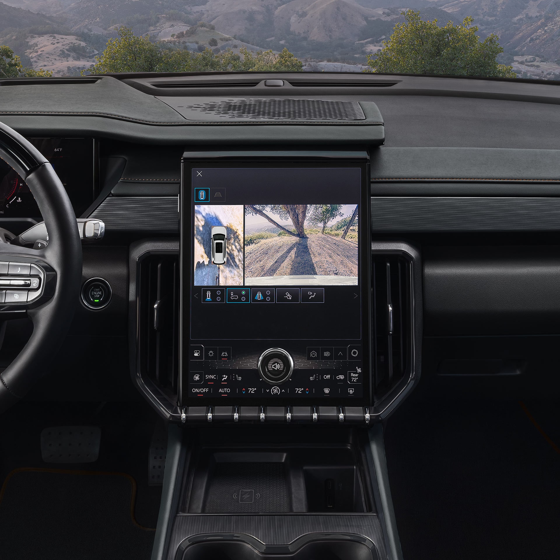 Le tableau de bord intérieur d’un VUS GMC Acadia 2027 montre un grand écran tactile central affichant une vue caméra à 360 degrés d’un paysage accidenté.
