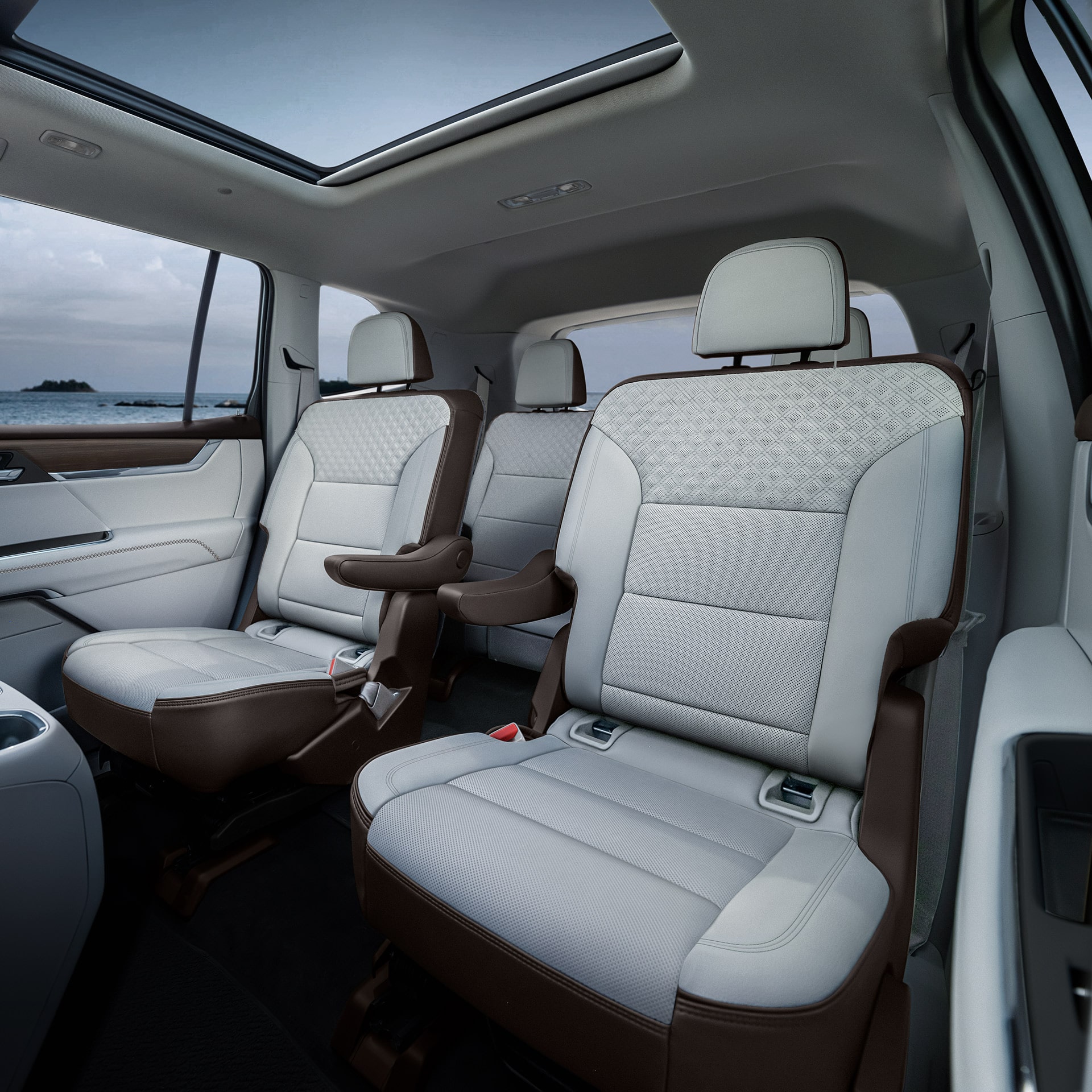 Les sièges arrière intérieurs d’un VUS GMC Acadia 2027 présentent des sièges en cuir blanc et brun avec des inserts à motifs et un toit ouvrant panoramique.