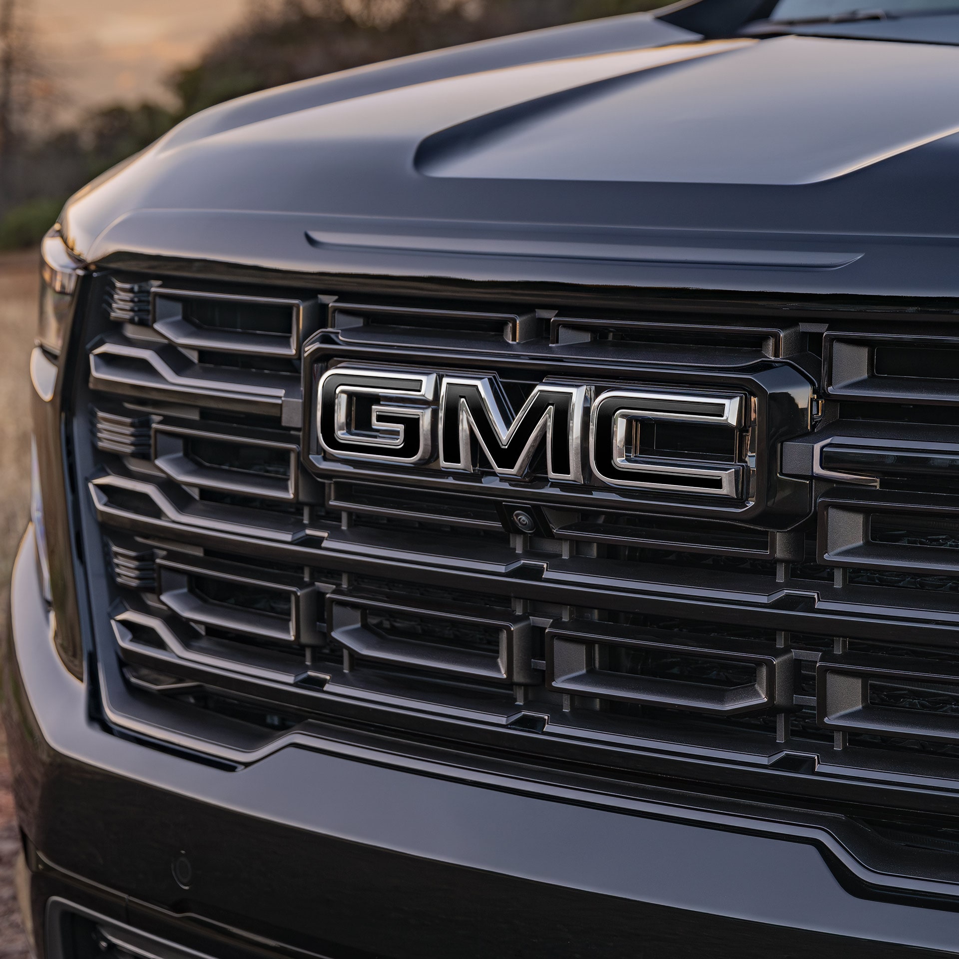 Un gros plan de la calandre avant d’un VUS GMC Acadia 2027 avec un logo GMC chromé.