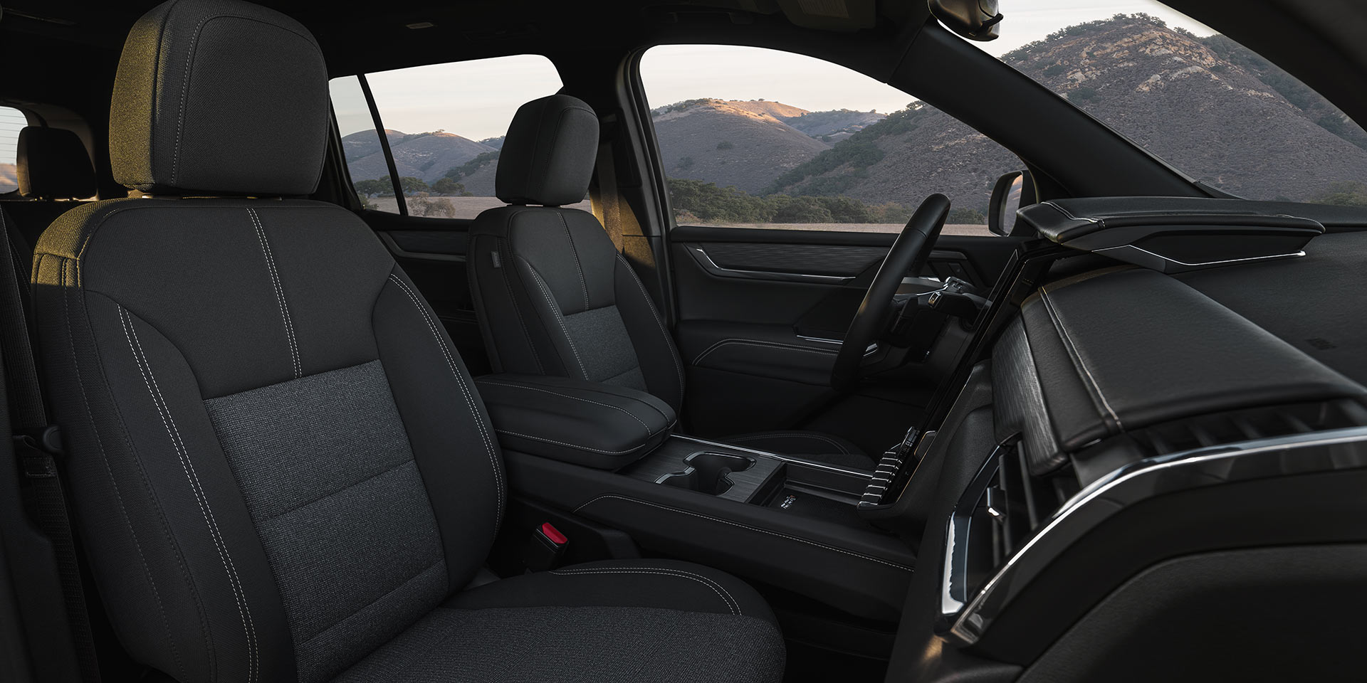 Les sièges avant intérieurs d’un VUS GMC Acadia 2027 avec tissu gris foncé et coutures blanches.