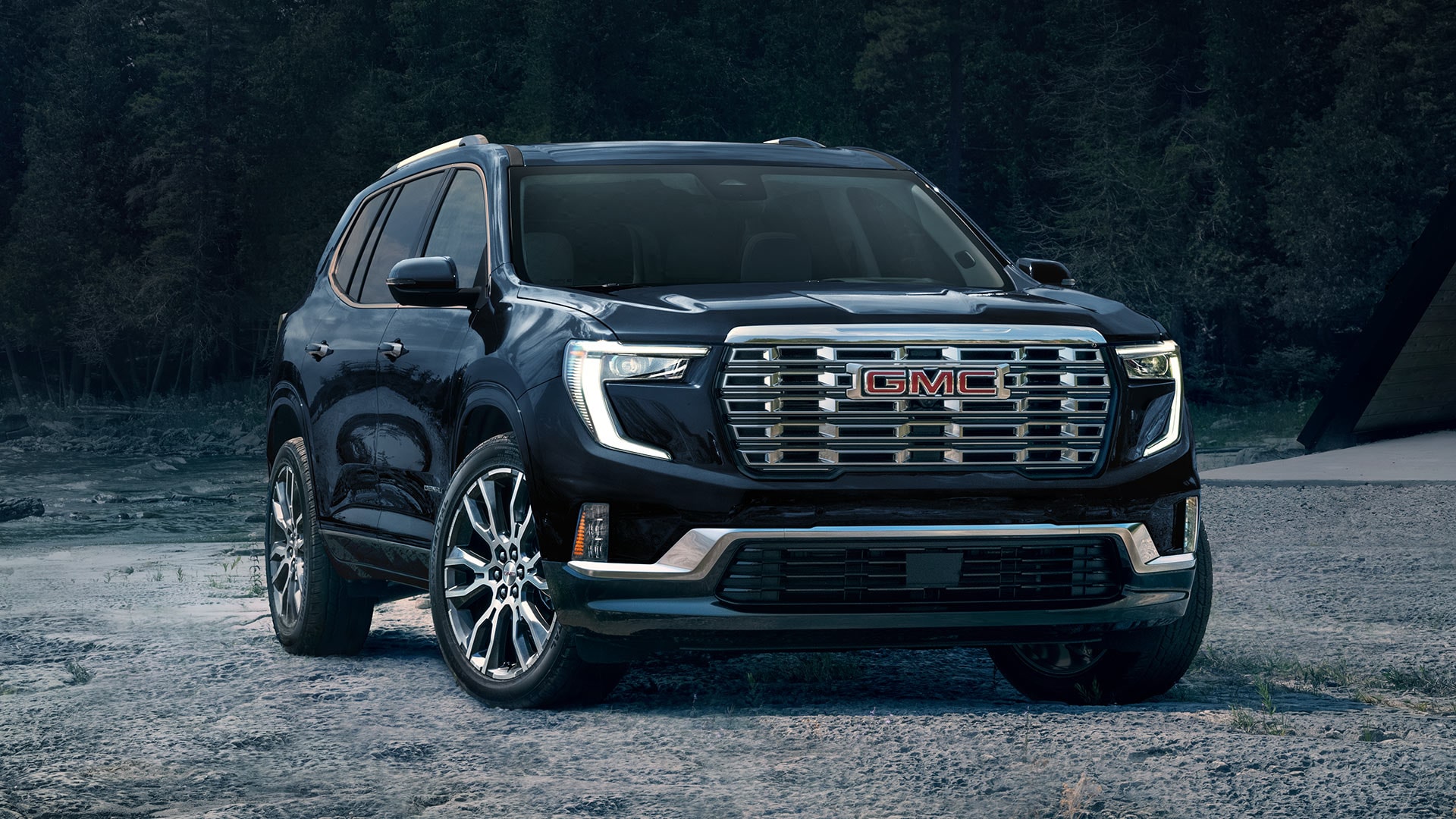 Vue de face d’une GMC Acadia 2027 stationnée sur une route de gravier.