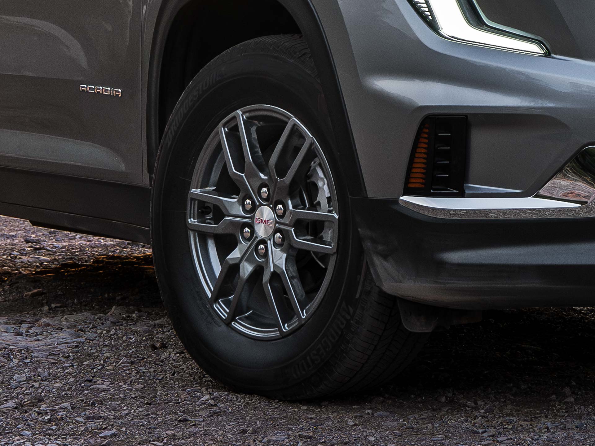 Gros plan de la section inférieure avant et d’une roue grise à rayons multiples d’un VUS GMC Acadia gris 2027.