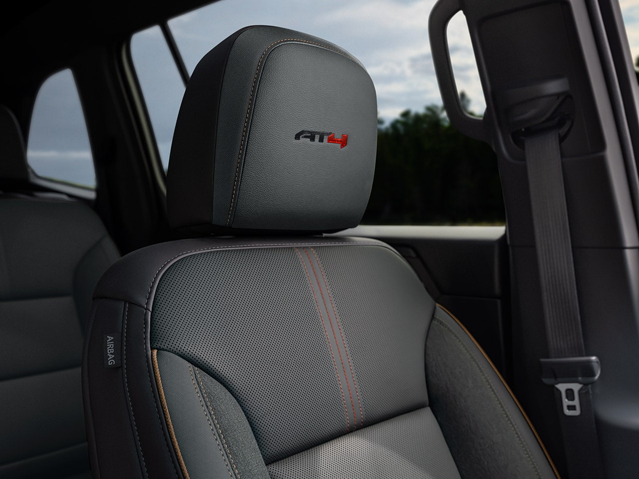 L’intérieur d’un VUS GMC Acadia AT4 2027 avec un siège en cuir gris avec le logo AT4 sur l’appuie-tête.