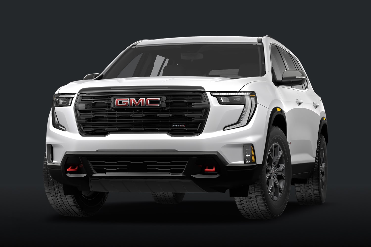 Un SUV GMC AT4 blanc, doté d'une calandre foncée et de touches de rouge, sur fond sombre