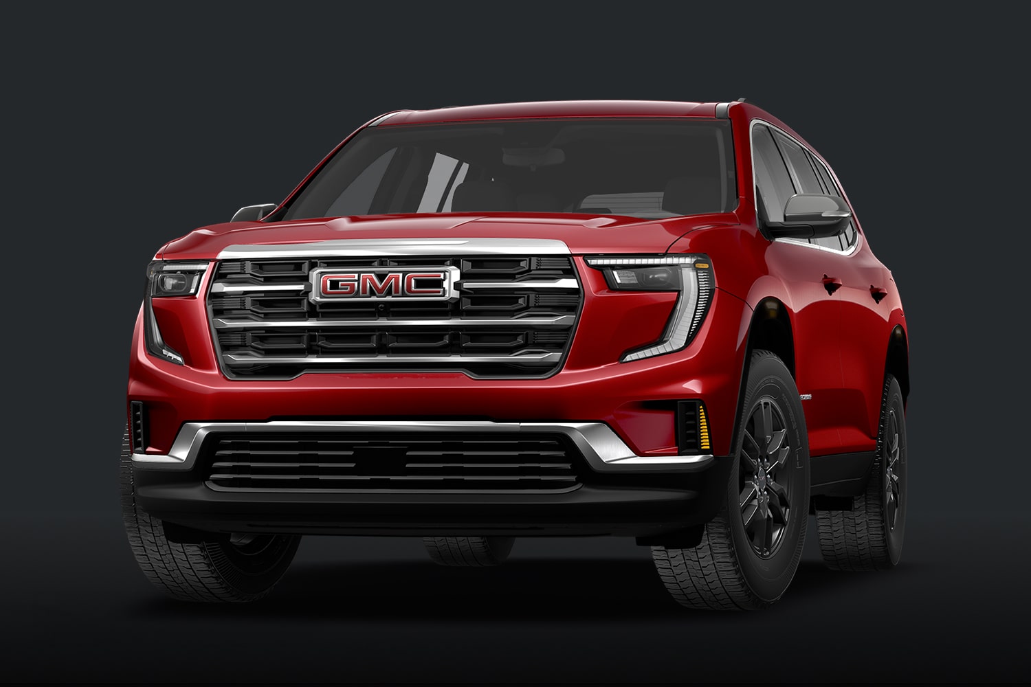 Un SUV GMC Elevation rouge, doté d'une calandre gris foncé, sur fond sombre