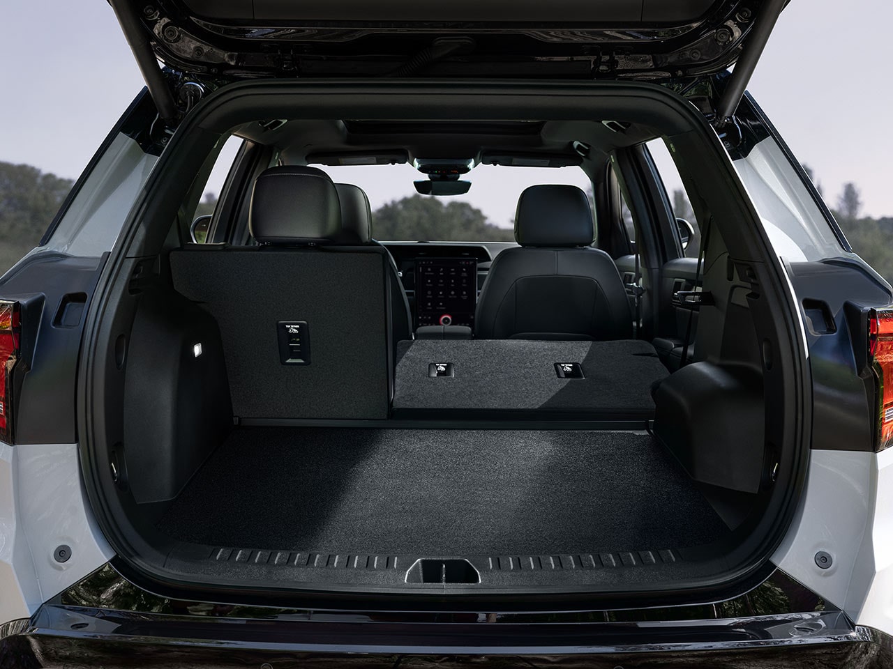 Un espace de chargement arrière ouvert d’un SUV terrain GMC blanc 2027 avec les sièges de la deuxième rangée rabattus à plat et un espace de rangement suffisant.