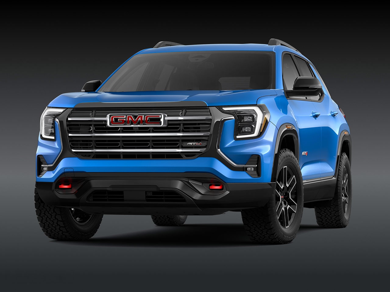 Une vue extérieure d’avant d’un SUV AT4 GMC Terrain 2027 bleu vif avec une calandre proéminente et des pneus robustes.