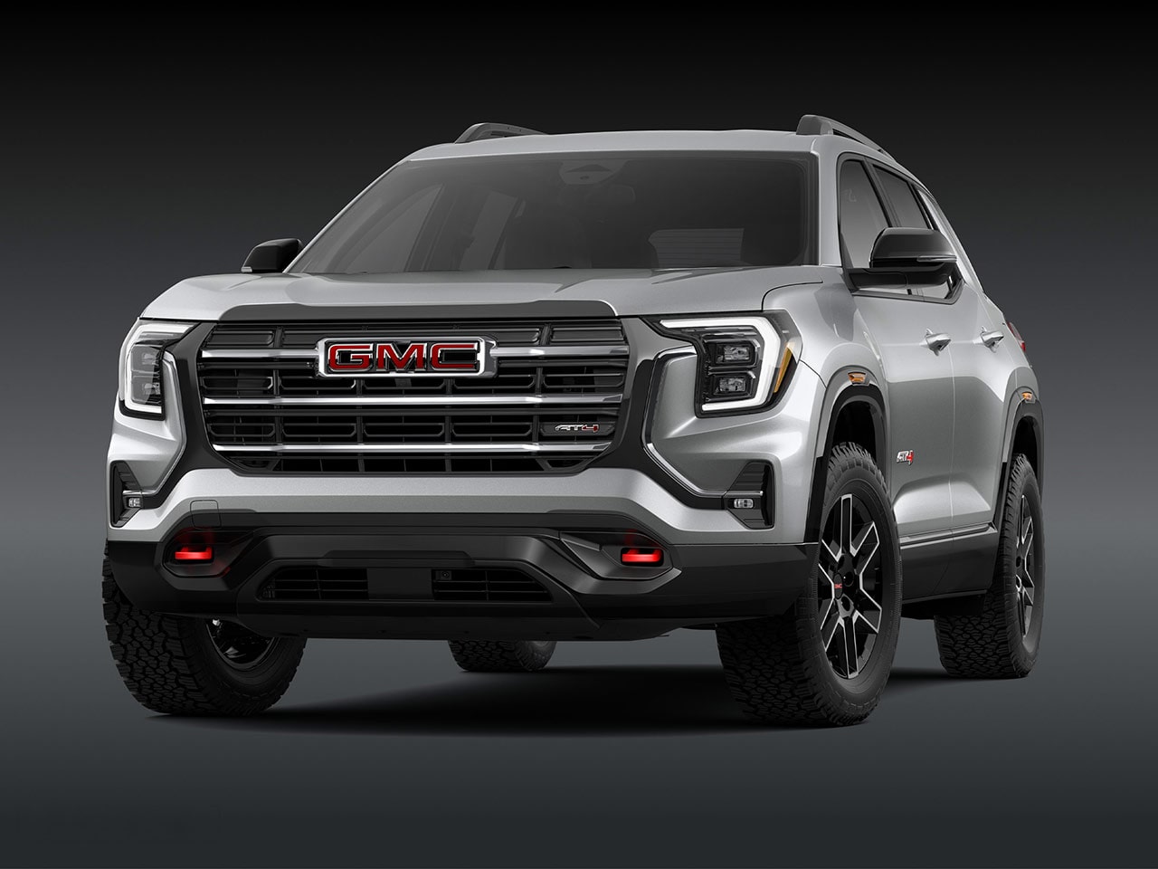 Vue extérieure d’avant d’un élégant SUV AT4 GMC Terrain 2027 argenté avec une calandre proéminente, des phares et des pneus robustes.