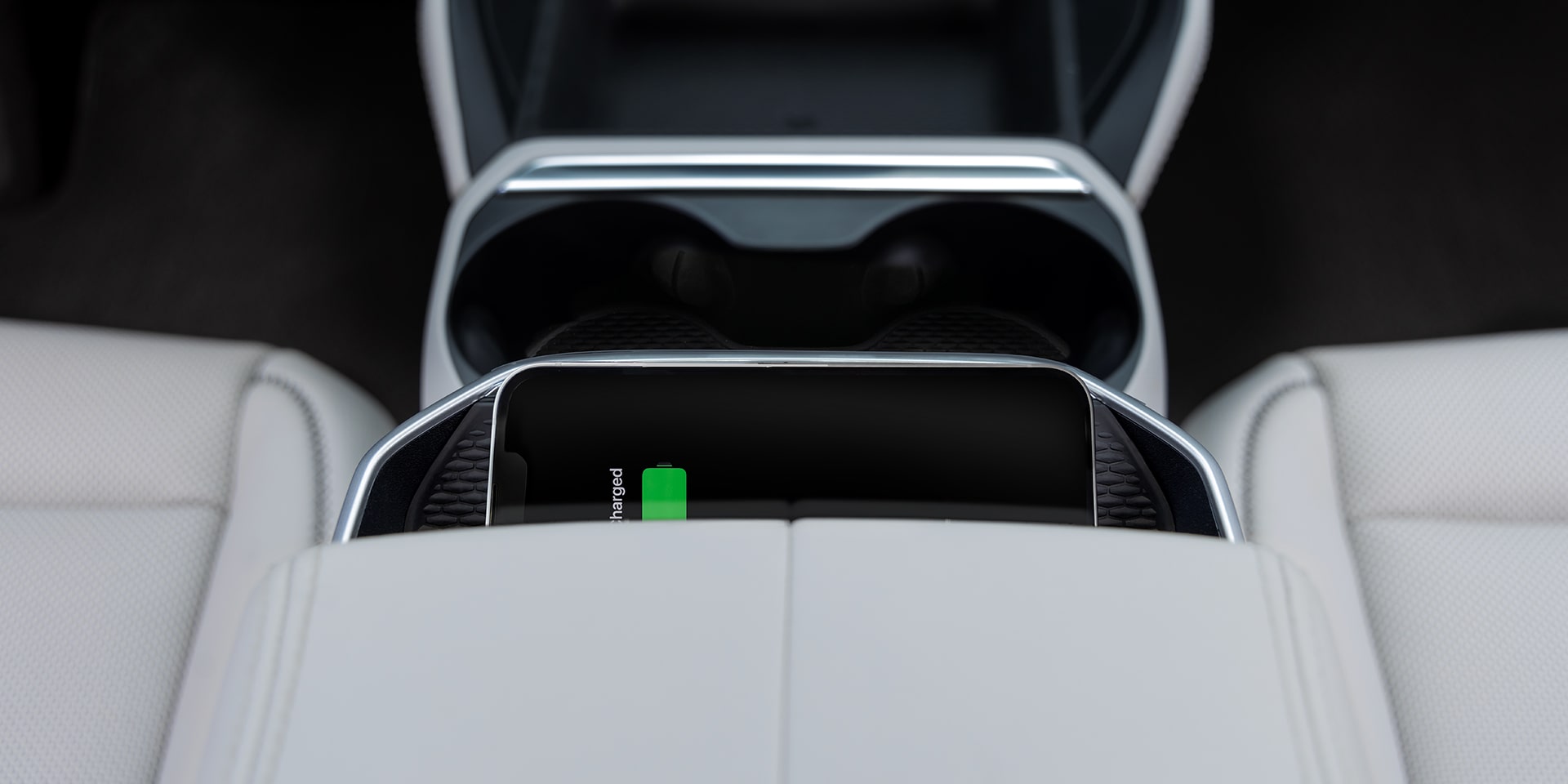 Un smartphone se recharge sans fil dans la console centrale d’un véhicule GMC Terrain 2027 avec des sièges de couleur claire.