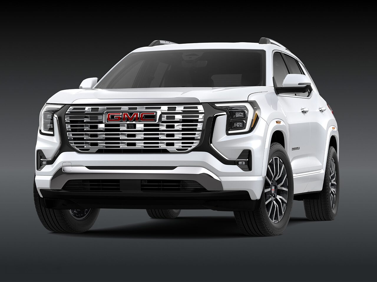 A Front Three-Quarter View of the White 2026 2027 GMC Terrain Denali SUV on a Dark Background.